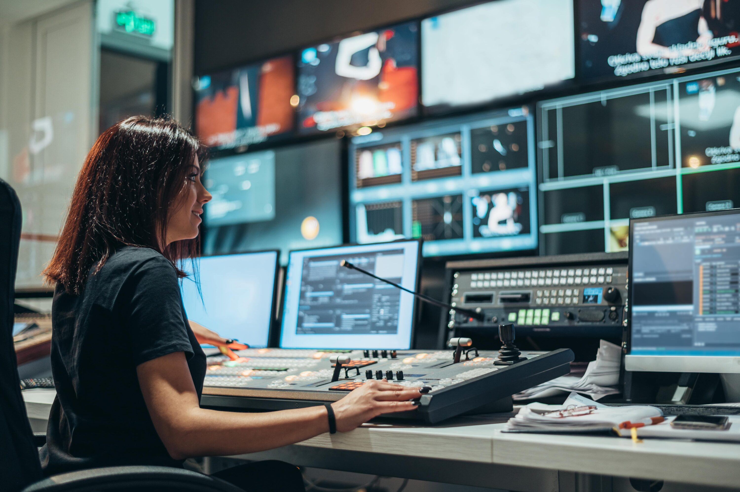 woman sits in tv control room, where monitoring and alerts notify her of issues with the video